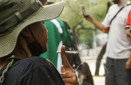 A man on Jan. 25, 2022, smokes a joint at a rally near the tourism ministry in Bangkok. Photo: Chayanit Itthipongmaetee / Coconuts
